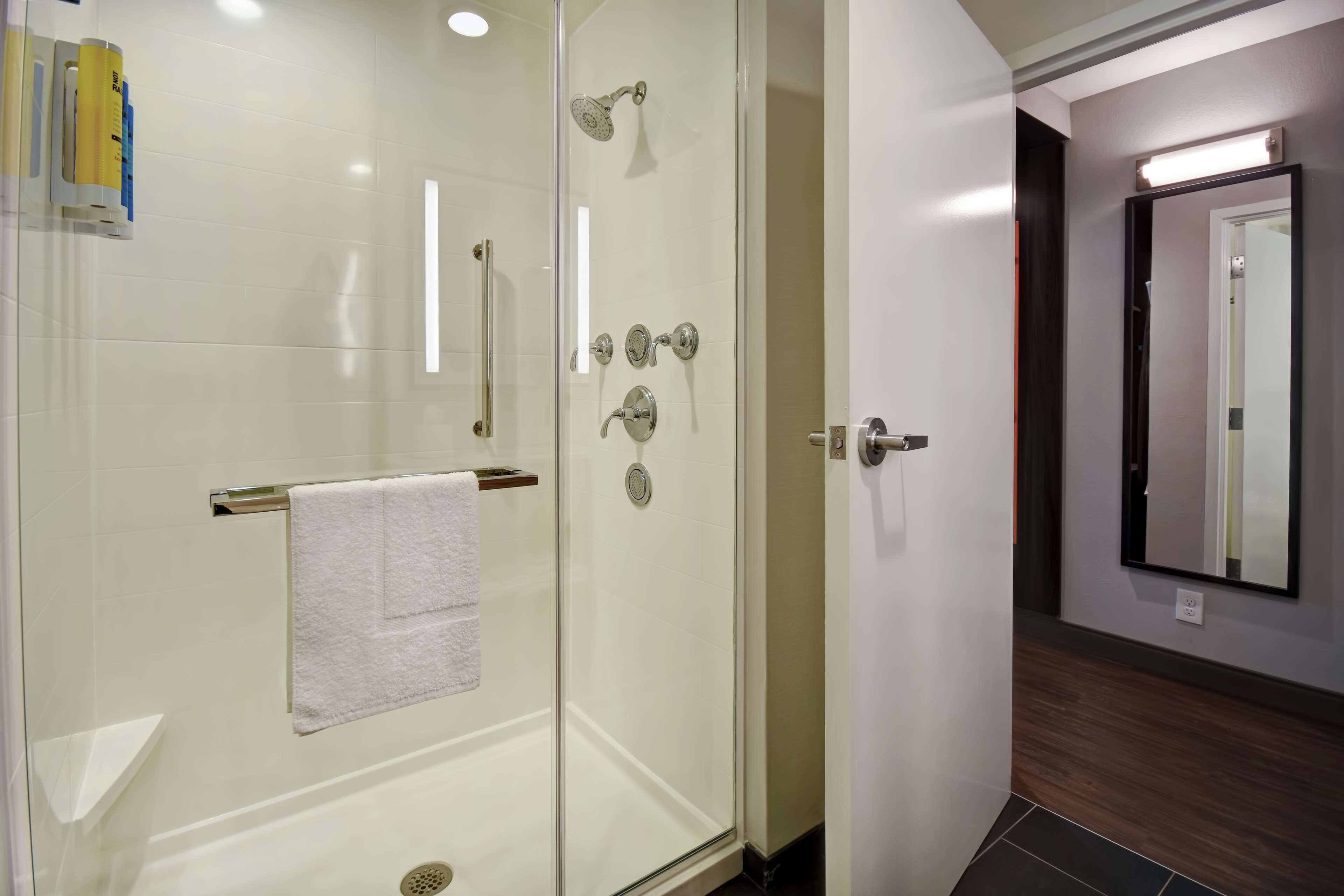 A modern bathroom with a glass-enclosed shower, a white towel hanging on a rack, and a mirror on the wall.