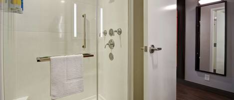 A modern bathroom with a glass-enclosed shower, a white towel hanging on a rack, and a mirror on the wall.