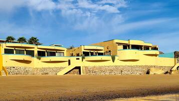 Un bâtiment situé sur la côte, à plusieurs étages, avec des fondations en pierre et un ciel dégagé.