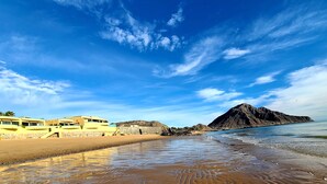 Une plage avec une montagne en arrière-plan et un bâtiment doté de nombreux balcons.
