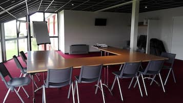 Ein Konferenzraum mit einem langen Tisch, Stühlen, einer Whiteboard-Tafel und einem Projektor.