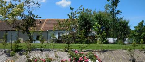 A residential area with a house, a garden with flowering plants, and a clear blue sky.