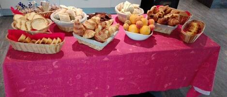 Une table où sont présentés divers aliments, notamment du pain, des pâtisseries et des fruits.
