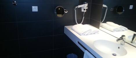 Un baño moderno con un lavamanos blanco, un espejo y dos dispensadores de toallas.