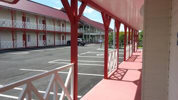 A motel with a red and white exterior, a covered parking area, and a building with multiple windows and balconies.