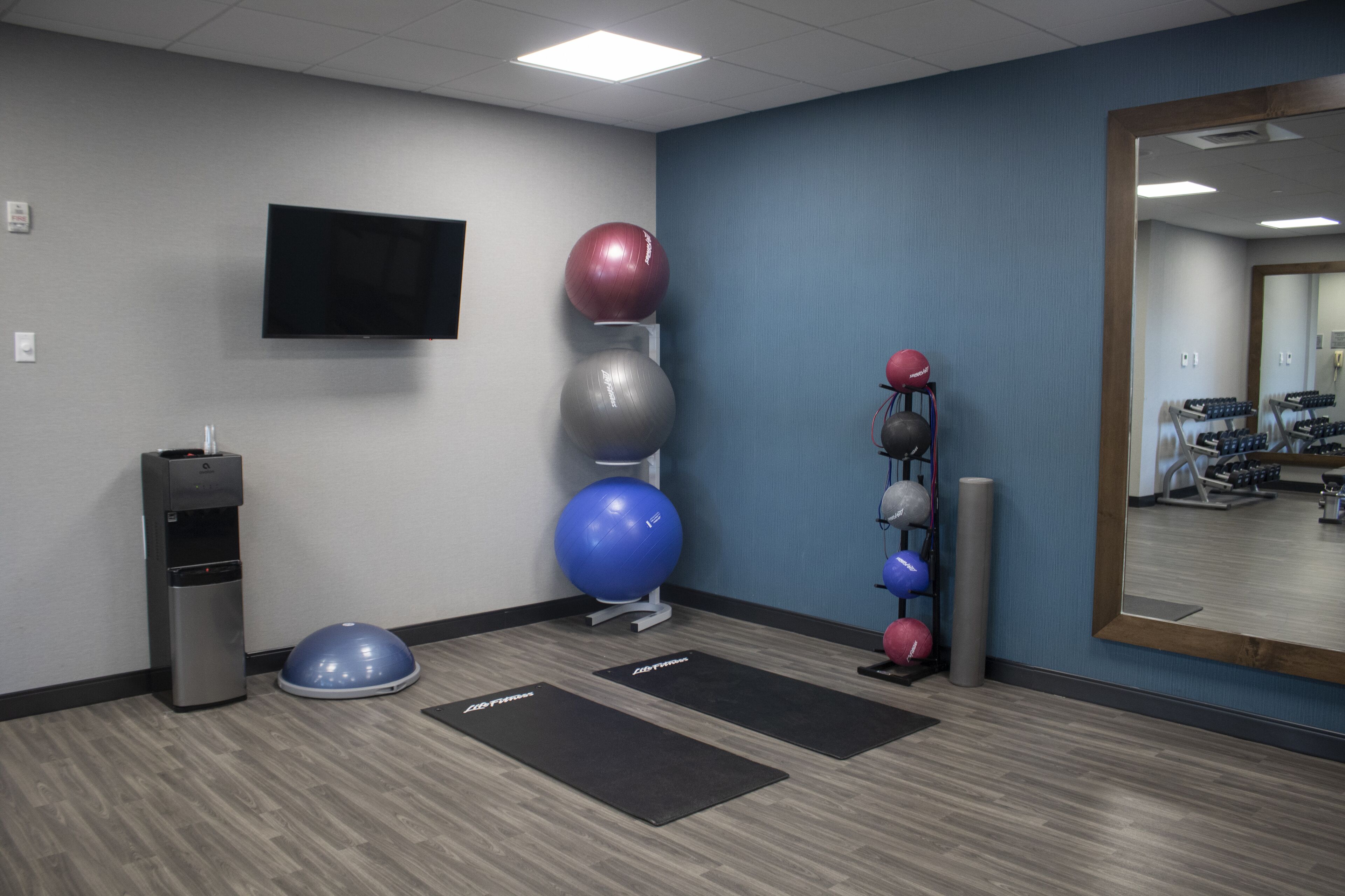A fitness room with exercise balls, a water dispenser, and exercise mats.