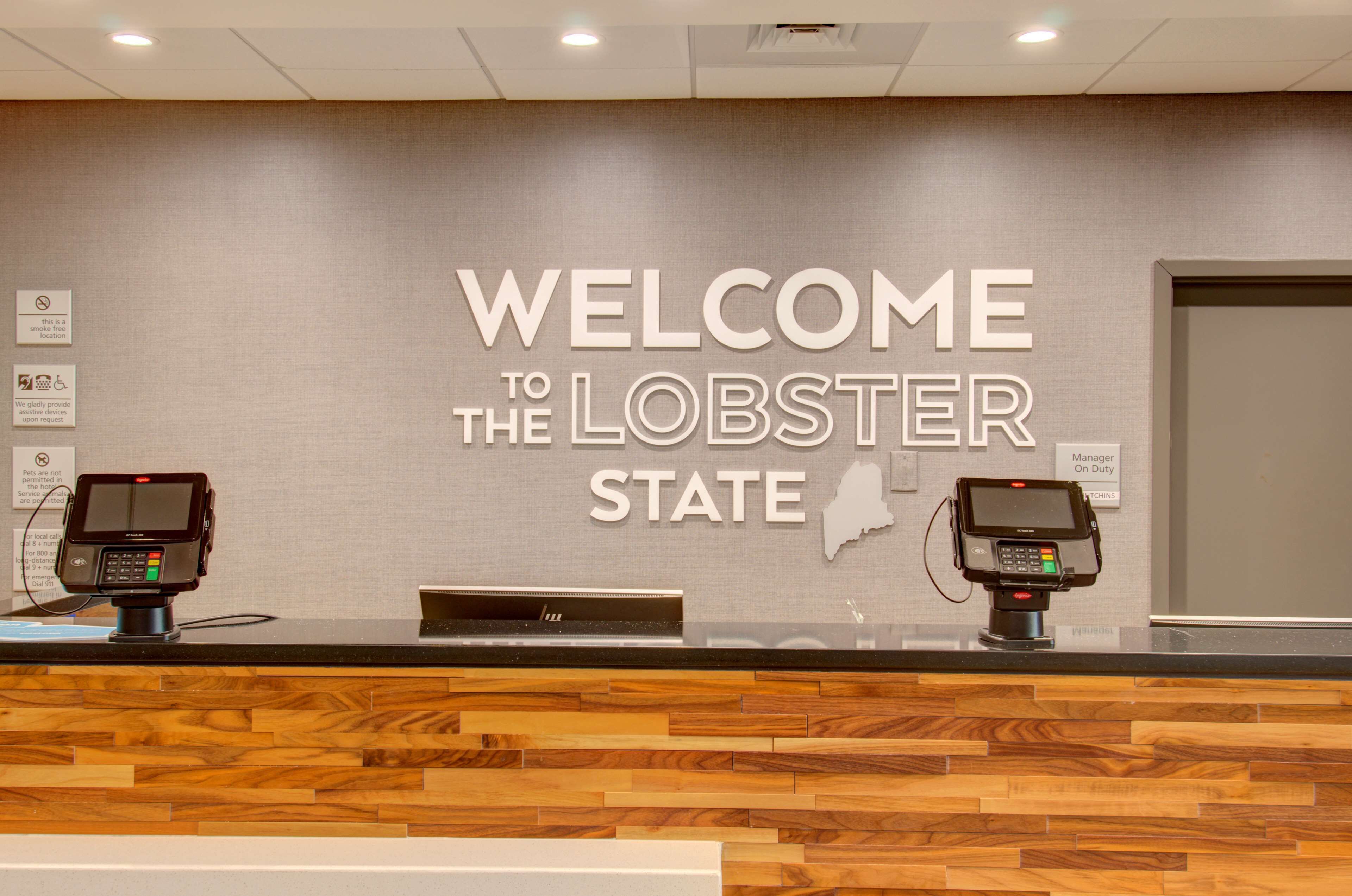 A reception desk with a wooden design and two self-service kiosks.