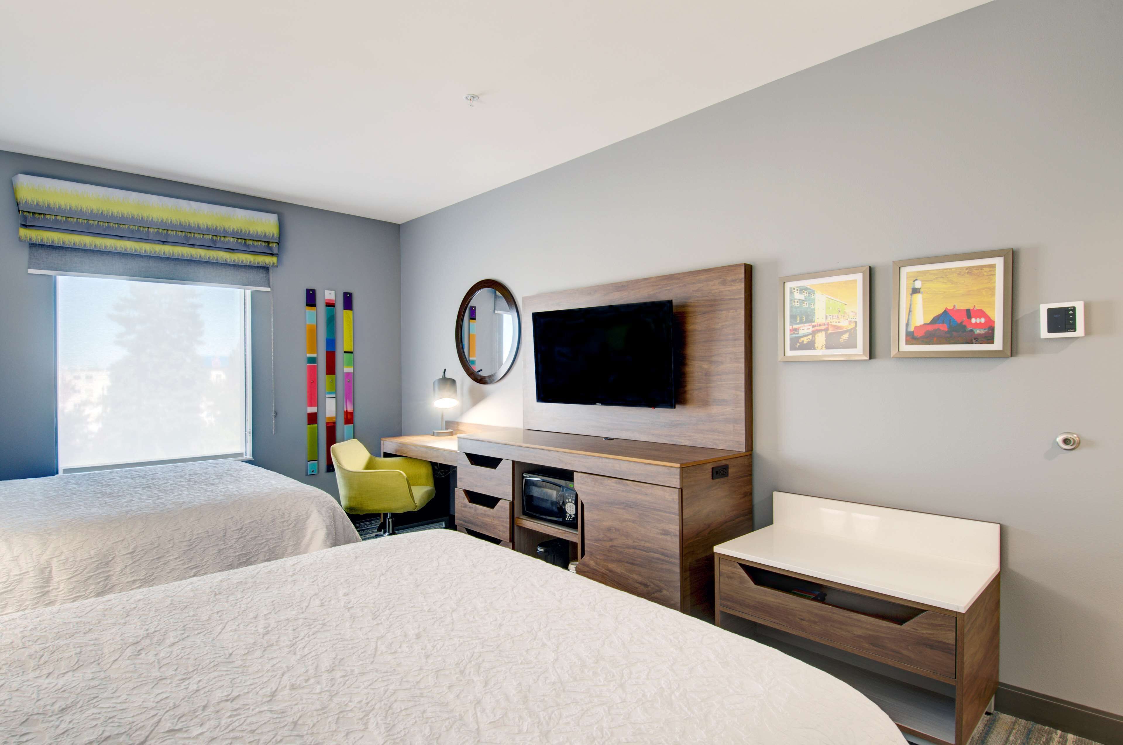 Una habitación de hotel moderna con dos camas, televisión, escritorio y una silla.