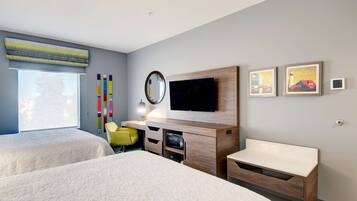 Una habitación de hotel moderna con dos camas, televisión, escritorio y una silla.