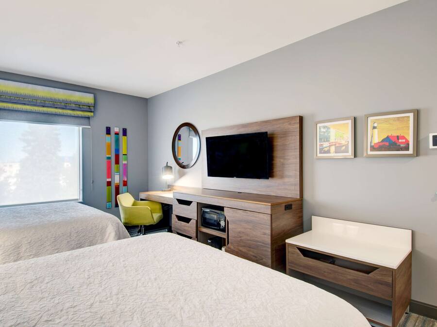 Una habitación de hotel moderna con dos camas, televisión, escritorio y una silla.