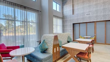Relax in a spacious room with a comfortable seating area, dining table, and large window with sheer curtains.