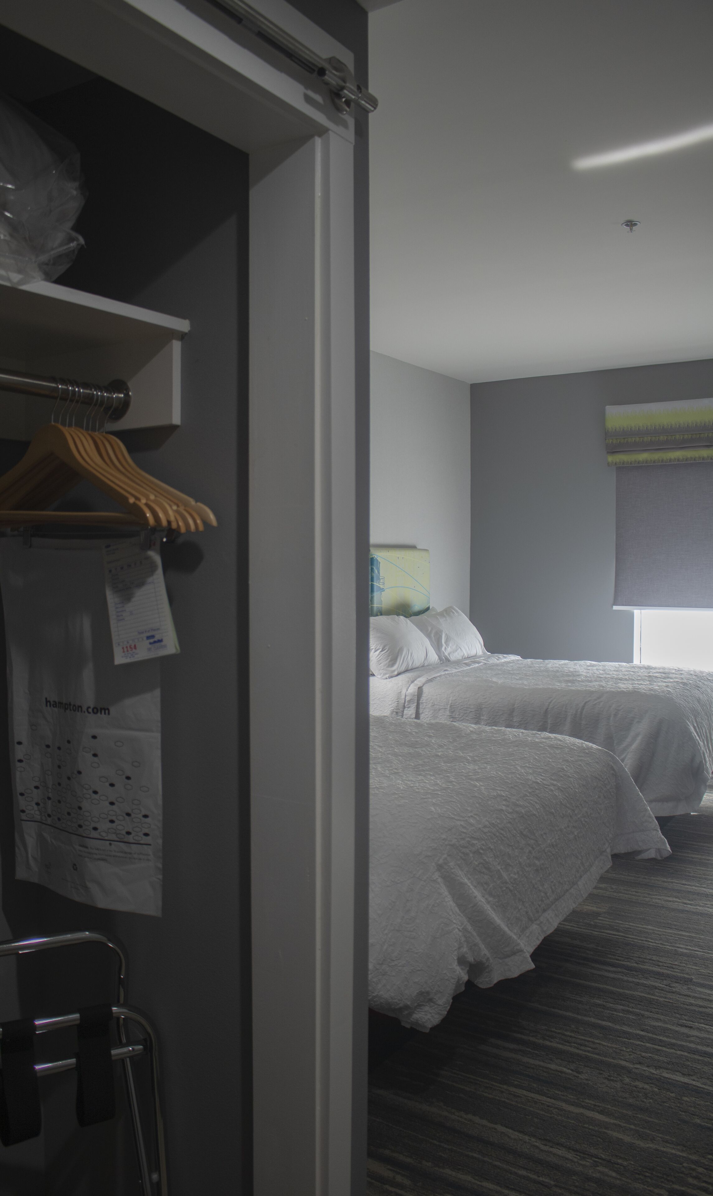 A hotel room with two beds, a wardrobe, and a window with a view.