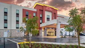 Hotel Hampton Inn & Suites com design moderno, fachada de pedra e entrada acolhedora.