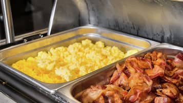 A buffet with scrambled eggs and bacon.