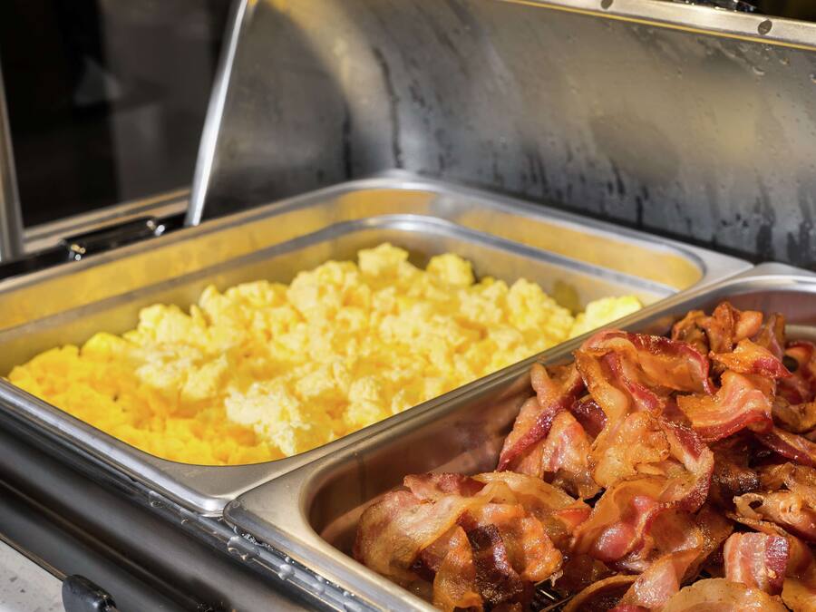 A buffet with scrambled eggs and bacon.