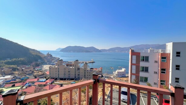 Un paisaje costero con edificios residenciales, un puerto deportivo y montañas al fondo.