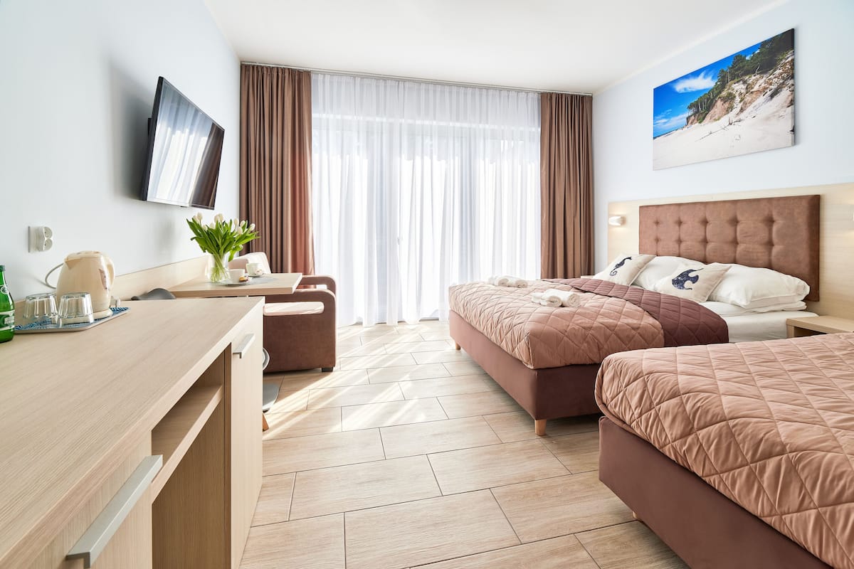 Ein Hotelzimmer mit Bett, Schreibtisch, Sessel und Fernseher.