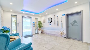A reception area with a blue sofa, a clock, and a door labeled "Villa Polna."