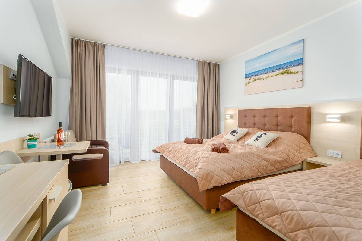 Ein modernes Hotelzimmer mit Bett, Schreibtisch und Fernseher.