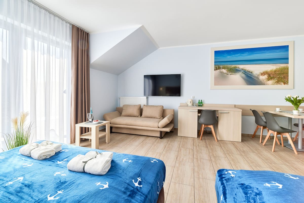 Ein Hotelzimmer mit Bett, Schreibtisch, Sofa und Fernseher.