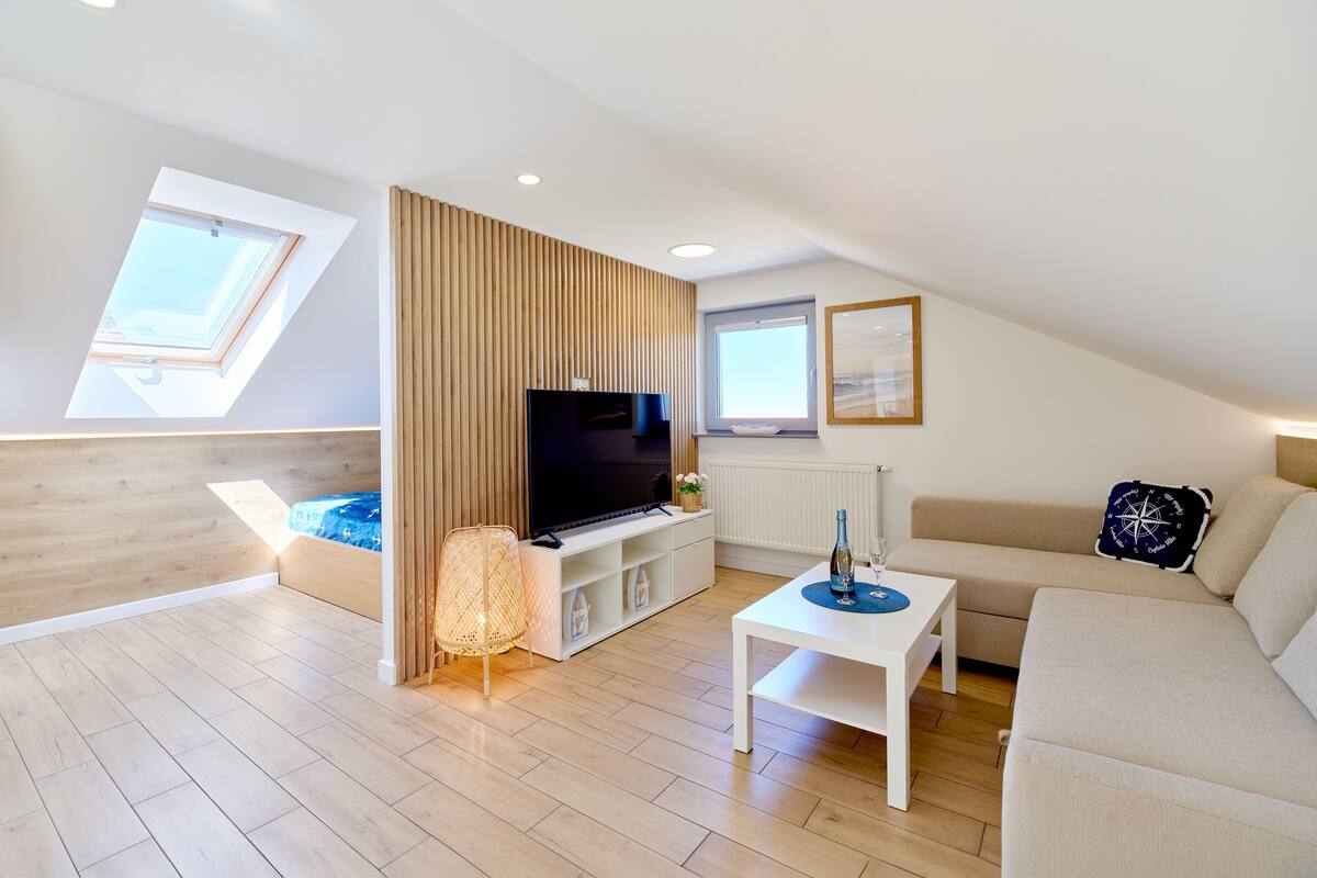 Ein modernes Loft-Apartment mit großem Fernseher, einer Couch, einem Couchtisch und einer Wand als Holzdekor.