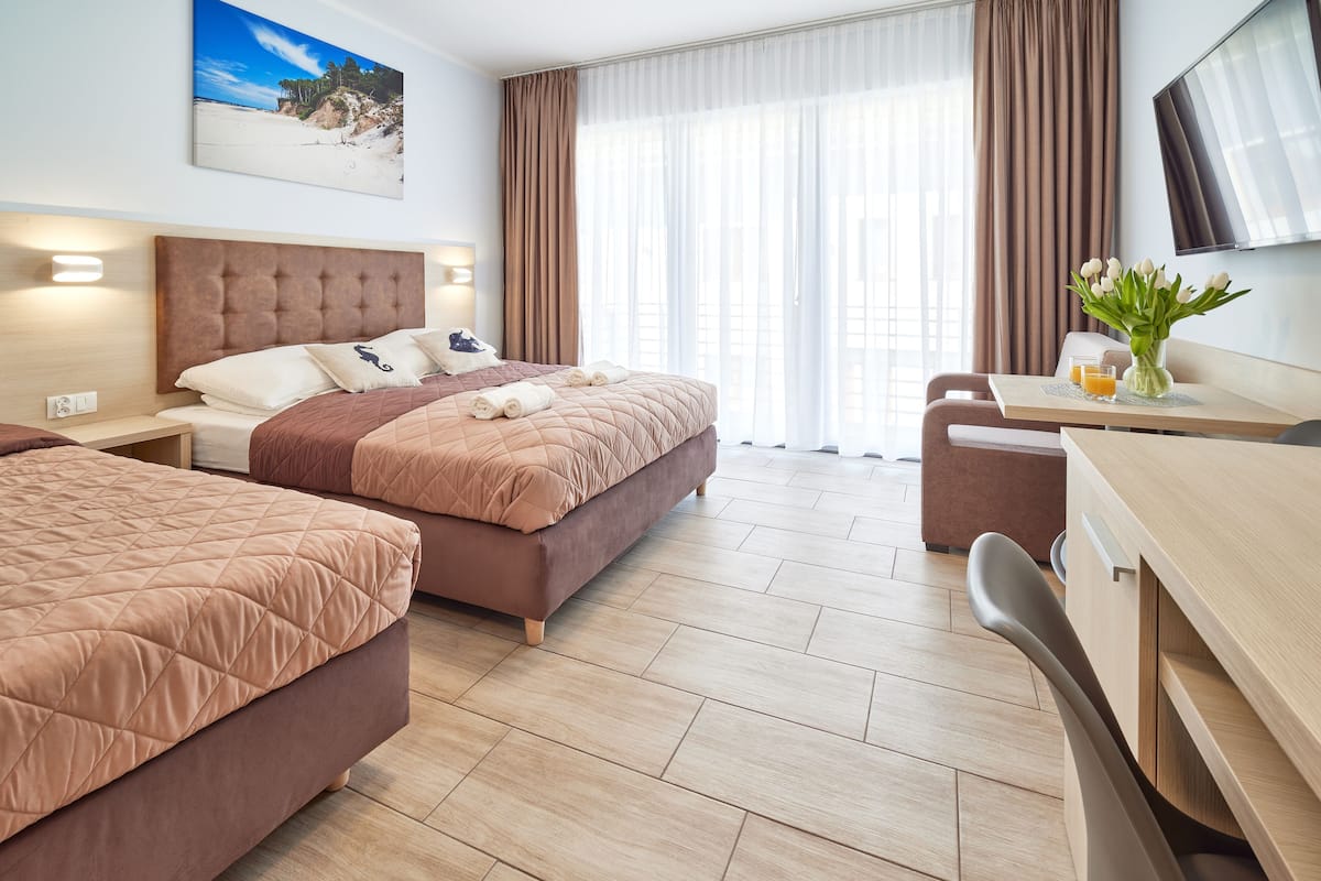Ein Hotelzimmer mit zwei Betten, einem Schreibtisch und einem Fernseher.