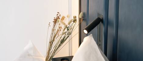A bed with white pillows, a black bedside table, and a wall-mounted lamp.