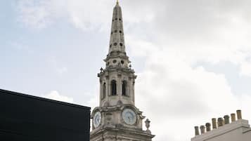 A clock tower with a pointed spire and a weather vane at the top.