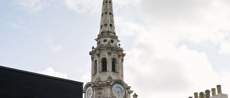 A clock tower with a pointed spire and a weather vane at the top.