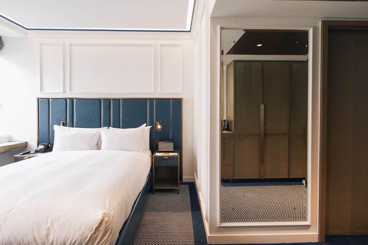 A hotel room with a large bed, a nightstand, a desk, and a walk-in closet.