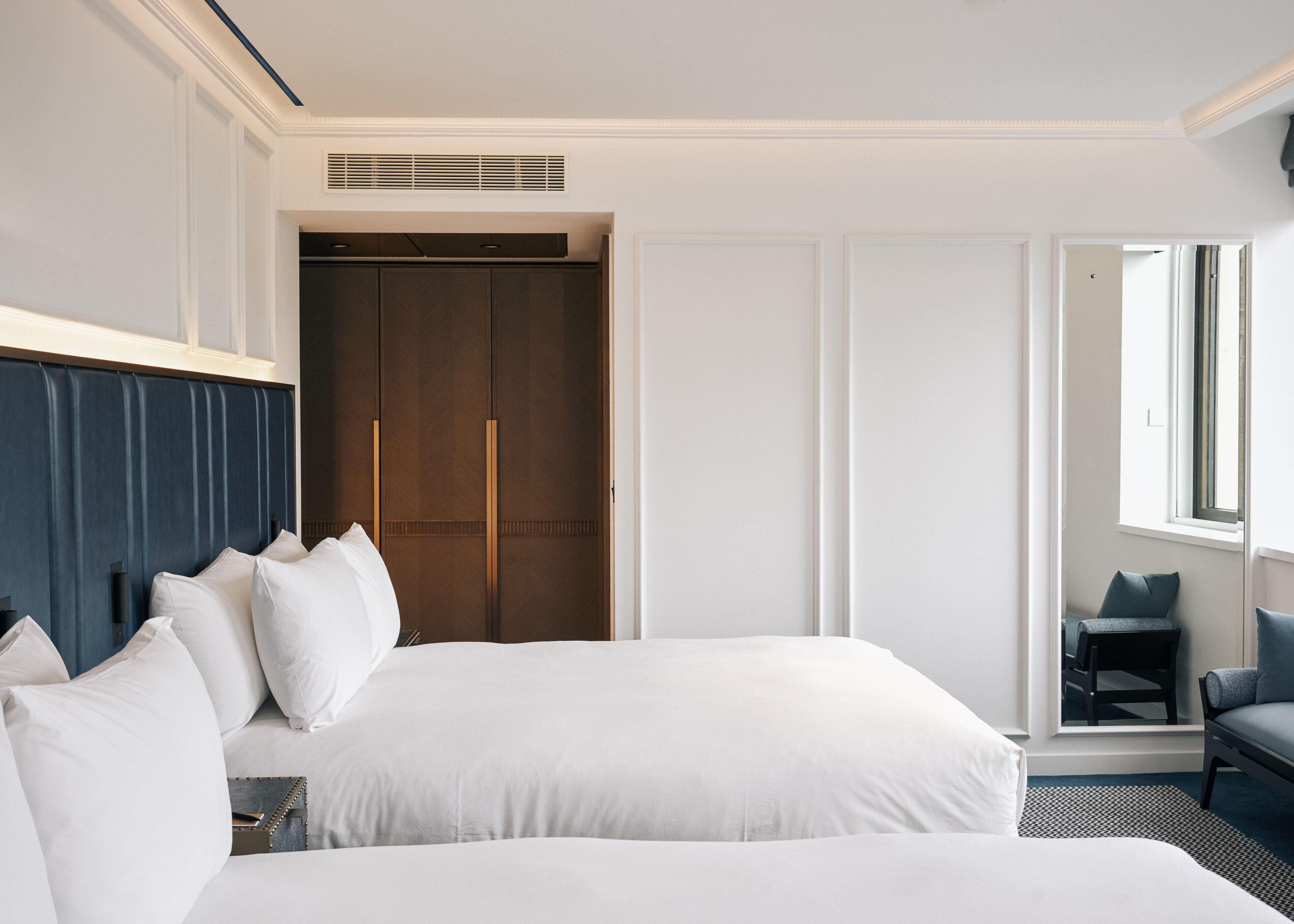 A hotel room with a large bed, a wardrobe, a seating area, and a window.