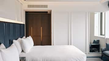 A hotel room with a large bed, a wardrobe, a seating area, and a window.