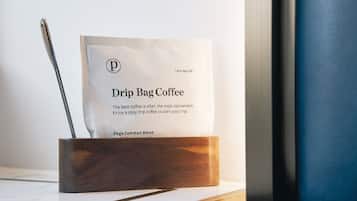 Een koffiezakje met druppelsysteem in een houten houder op een tafel.