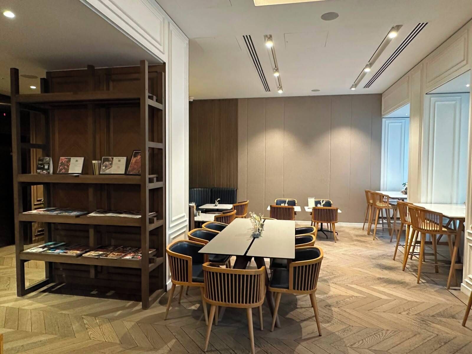 Un comedor moderno con mobiliario de madera y una estantería empotrada.