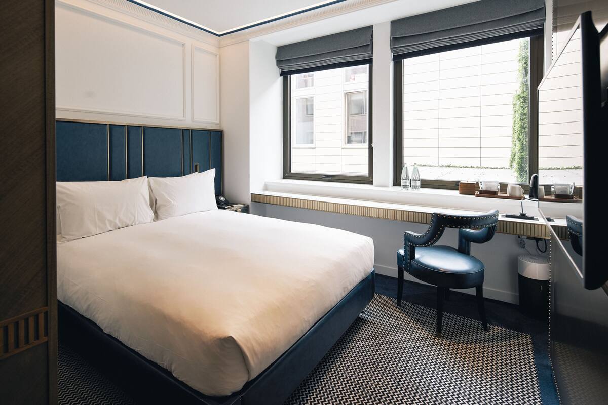 A hotel room with a bed, a desk, and a chair.
