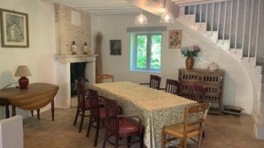 A dining area with a table and chairs, a fireplace, and a staircase. - Alfred and George, Le Gîte (Sainpuits)