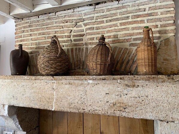A stone fireplace with three woven baskets and a dark vase on the mantel. - Alfred and George, Le Gîte (Sainpuits)