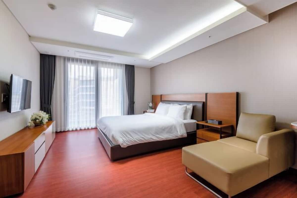 Ein Hotelzimmer mit einem Bett, Nachttischen, einem Fernseher, einem Sofa und einem Schreibtisch.