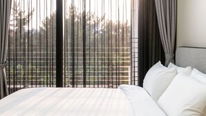 A hotel room with a large bed, a view through sheer curtains, and a grey headboard. - Seaside Arden (Seogwipo)