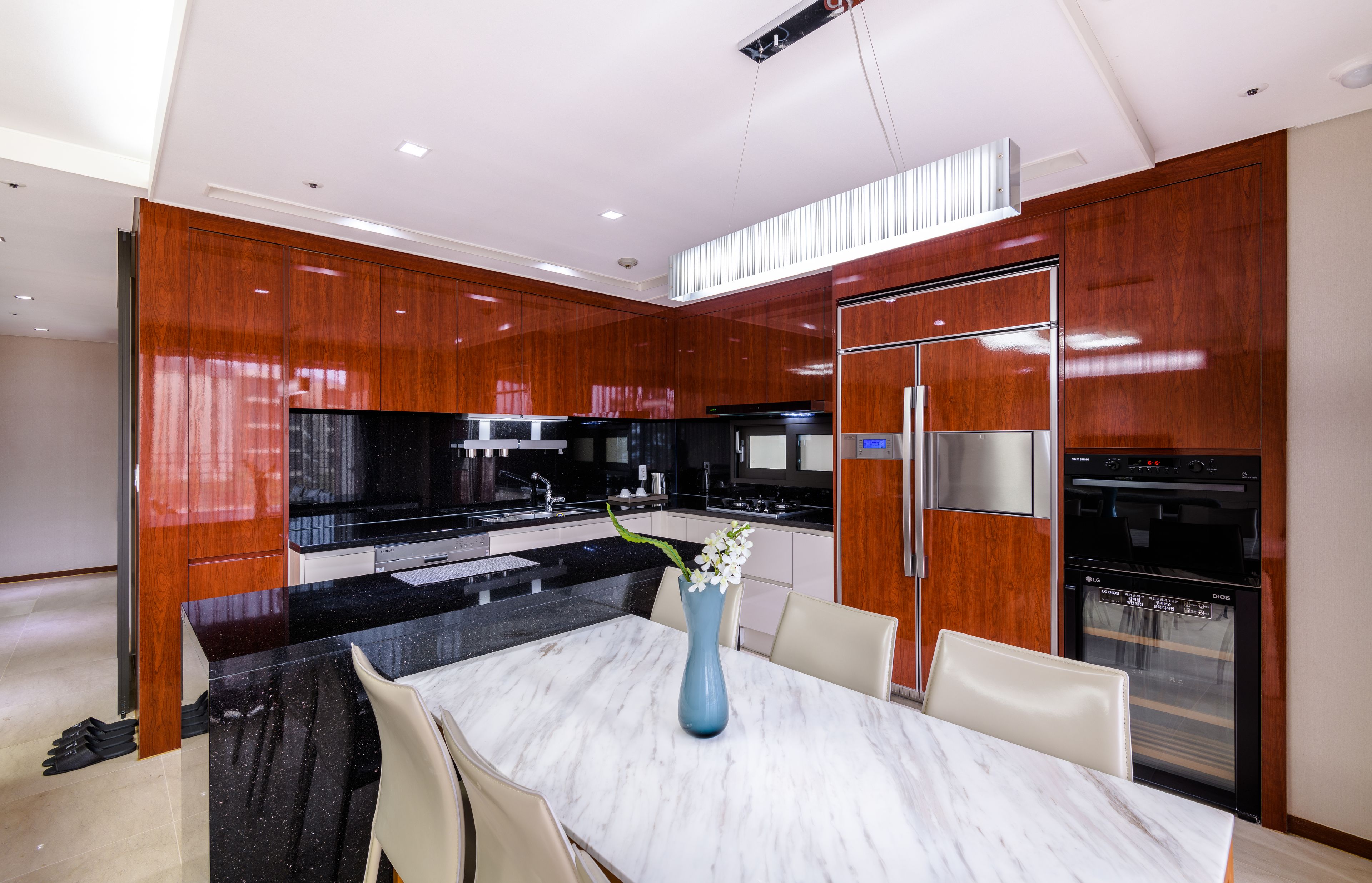 A modern kitchen with a marble island, wooden cabinets, and stainless steel appliances.