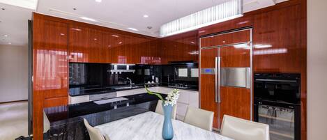 A modern kitchen with a marble island, wooden cabinets, and stainless steel appliances.