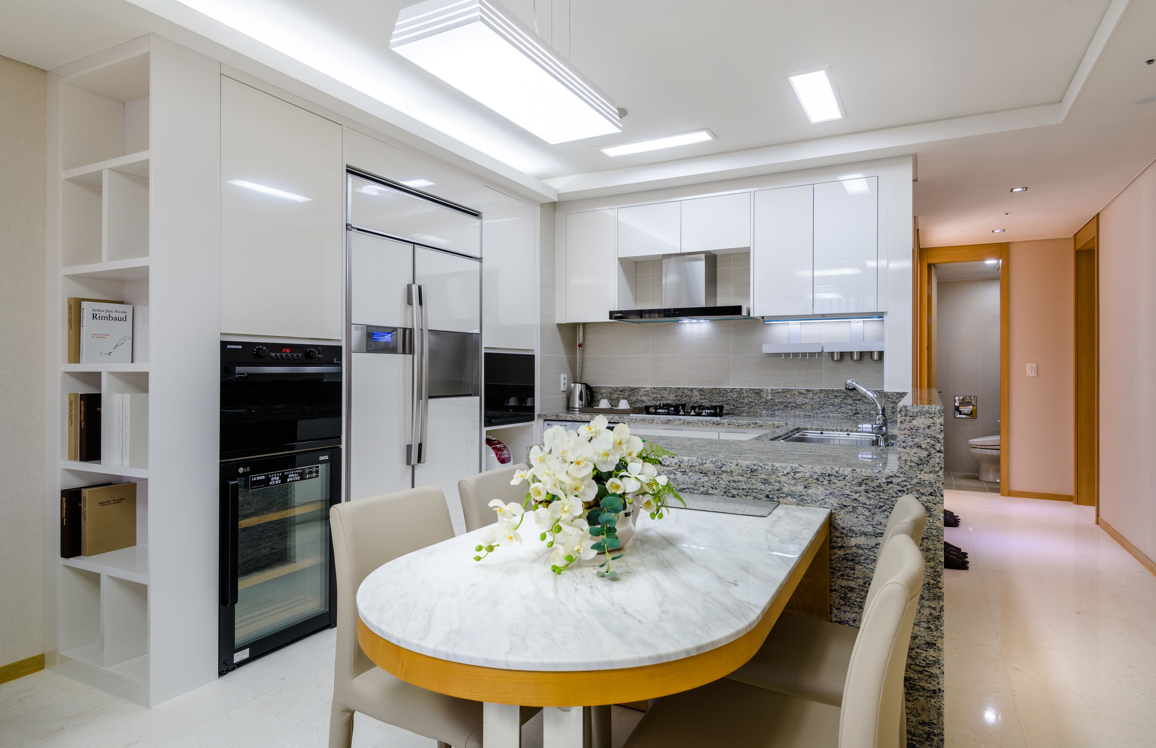 A modern kitchen with white cabinetry, a built-in oven, and a granite countertop.