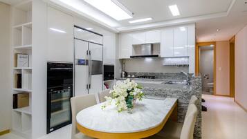 A modern kitchen with white cabinetry, a built-in oven, and a granite countertop.