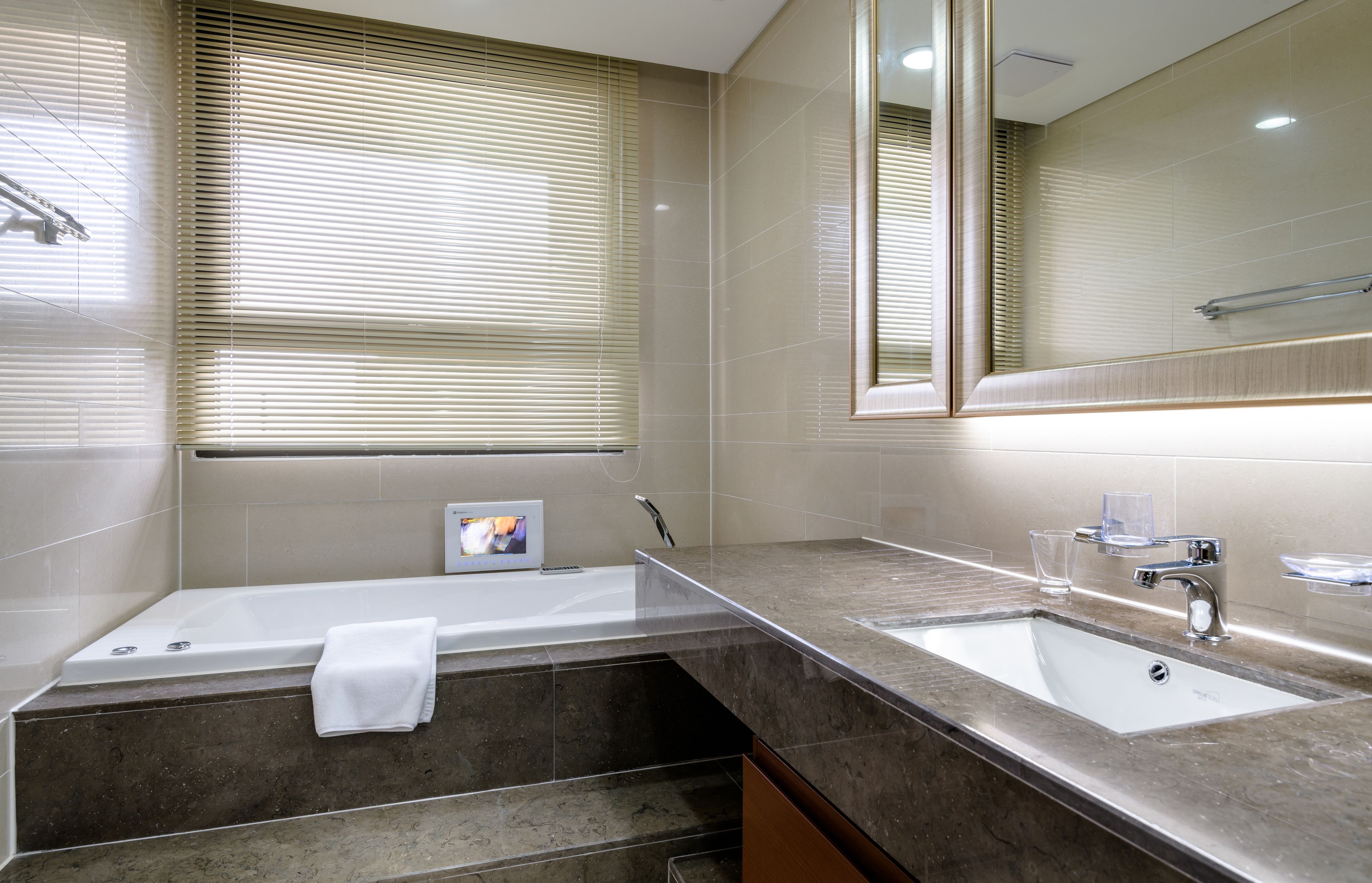 A modern bathroom with a bathtub, a sink, and a large mirror.