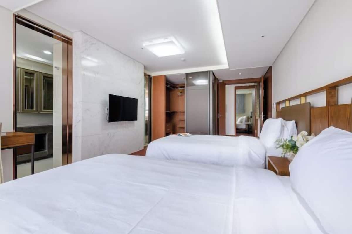 Ein Hotelzimmer mit zwei Betten, einem Fernseher, einem Spiegel und einem Holz-Kopfteil.