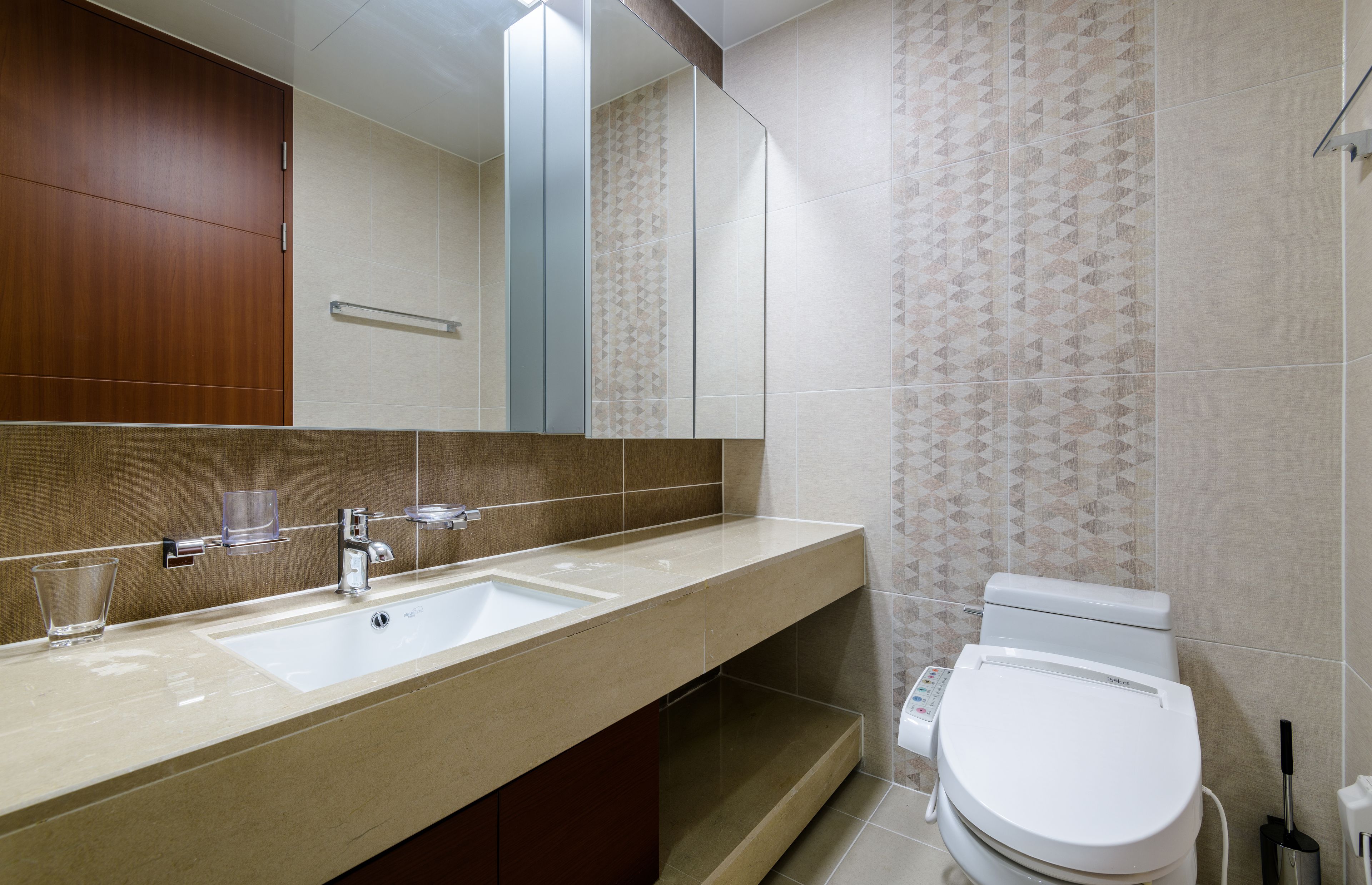 A modern bathroom with a large mirror, two sinks, a toilet, and patterned tiles.