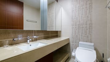 A modern bathroom with a large mirror, two sinks, a toilet, and patterned tiles.
