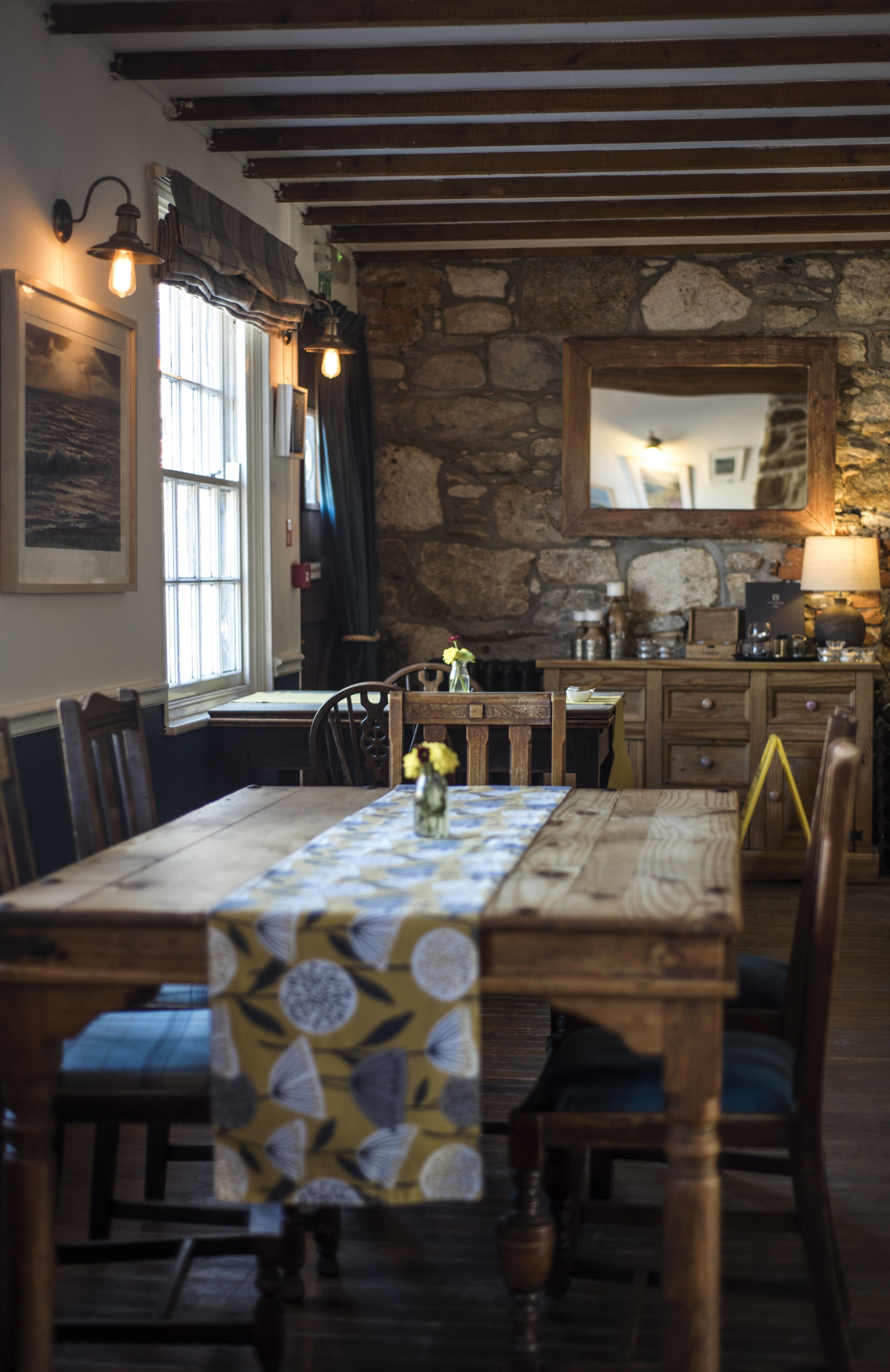 Un comedor rústico con una mesa de madera, sillas y una pared de piedra.