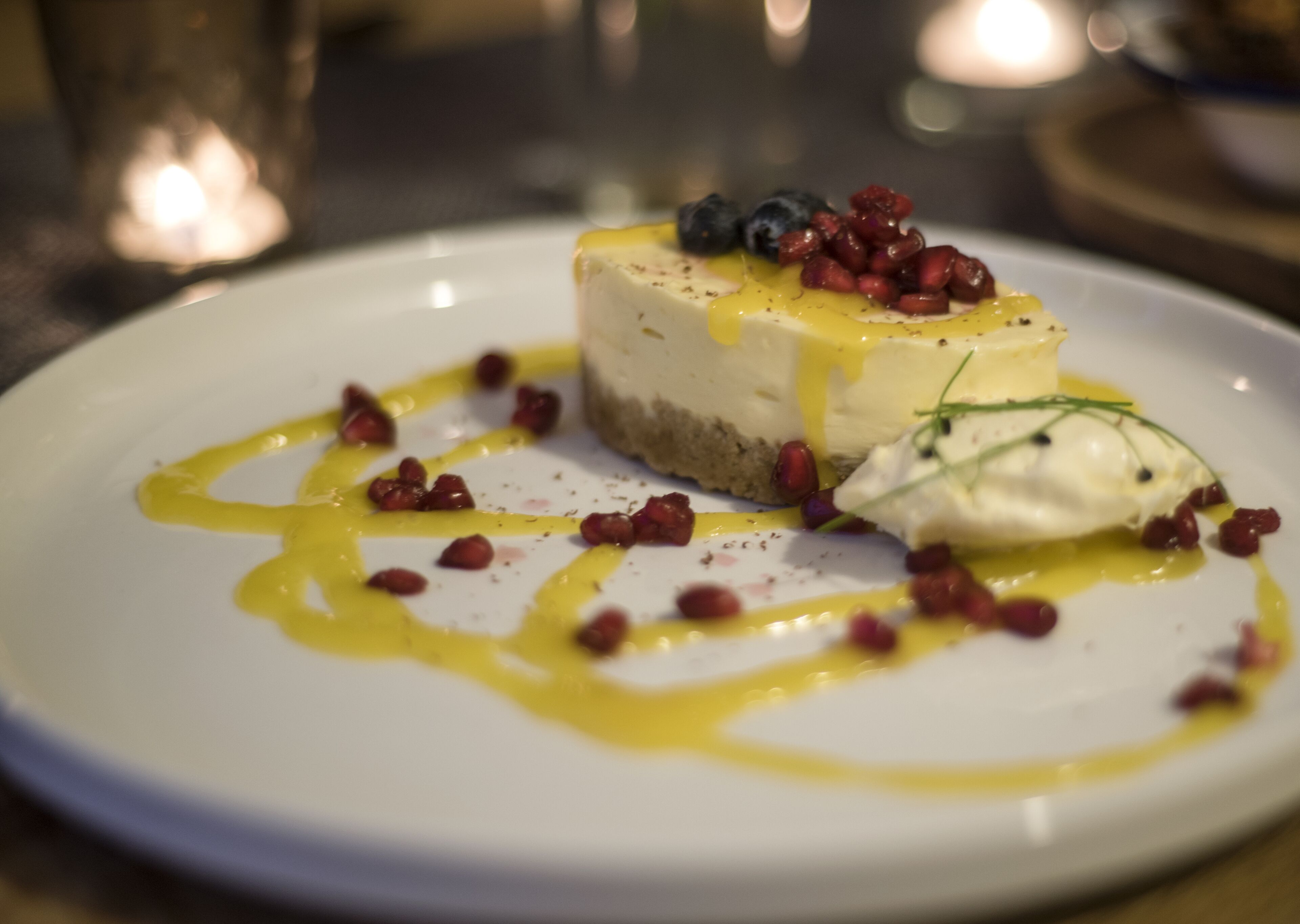 Een nagerechtenbord met cheesecake, bessen en saus.