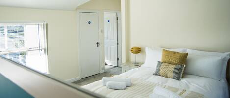 A hotel room with a bed, a nightstand, a lamp, and a door.